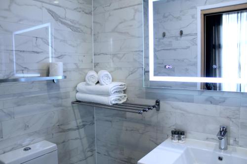 y baño con lavabo, espejo y toallas. en NOX Paddington, en Londres