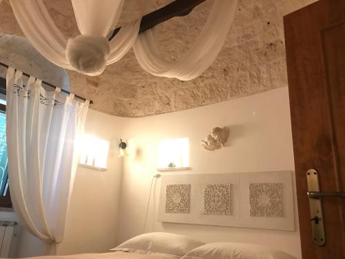 a bedroom with a bed with white curtains and a ceiling at Aria di Casa Country Resort in Alberobello