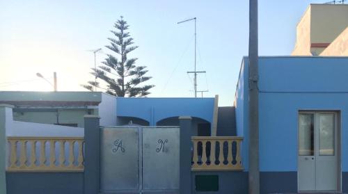 un edificio blu con una recinzione e un albero sullo sfondo di HOUSE ROMINA a Lendinuso
