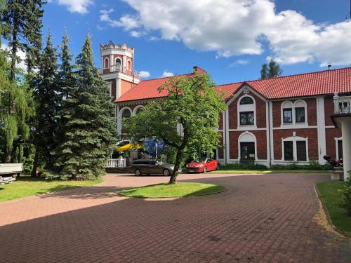 un edificio con una torre dell'orologio e un albero di fronte di Hotel Zameczek a Radomsko
