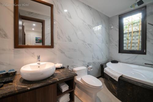 a bathroom with a sink and a toilet and a tub at Hillary Hanoi Hotel in Hanoi