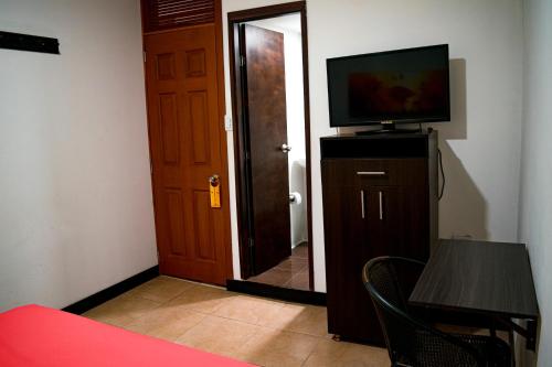 um quarto com uma porta, uma televisão e uma mesa em Casabella Hotel em Manizales