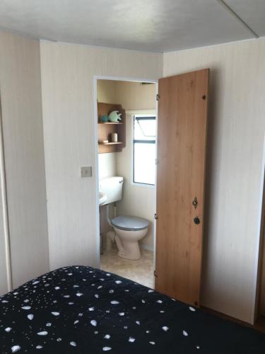 a bedroom with a bathroom with a toilet and a door at Caravan to Hire Dymchurch in Dymchurch