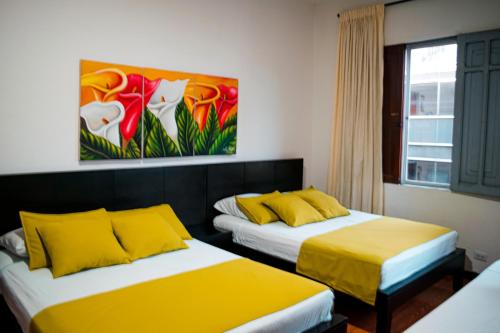 two beds in a room with a painting on the wall at Casabella Hotel in Manizales