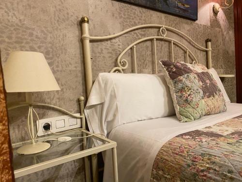 um quarto com uma cama e uma mesa de vidro com um candeeiro em Hostal Orleans em Barcelona