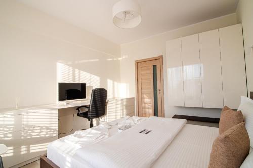 a white bedroom with a bed and a desk at BLISS Apartment in Constanţa
