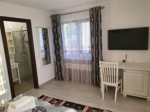 a living room with a television and a desk and a window at Casa Alexandru – Locul în care te simți acasă in Vişeu de Jos