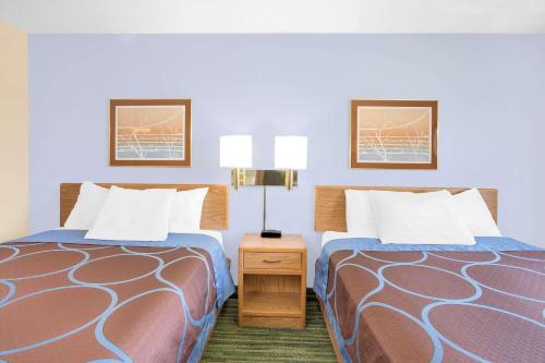Habitación de hotel con 2 camas y mesa con 2 lámparas en Boarders Inn & Suites by Cobblestone Hotels Waterloo Cedar Falls, en Waterloo
