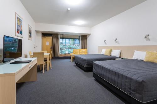 a hotel room with two beds and a desk at Mayfair Plaza Motel and Apartments in Hobart