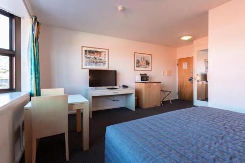 a hotel room with a bed and a desk at Mayfair Plaza Motel and Apartments in Hobart