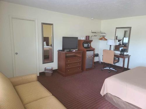 a bedroom with a bed and a desk with a television at Budget Inn - Farmington in Farmington