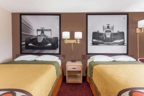 two beds in a hotel room with pictures of cars at Super 8 by Wyndham Shelton in Shelton