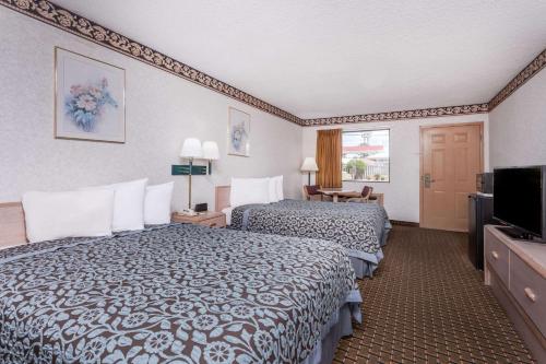 a hotel room with two beds and a flat screen tv at Days Inn by Wyndham Byron in Byron
