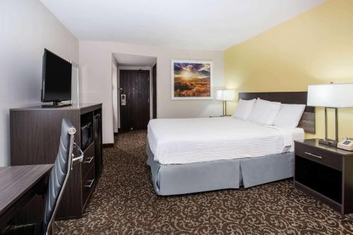 a hotel room with a bed and a flat screen tv at Days Inn by Wyndham Phoenix North in Phoenix