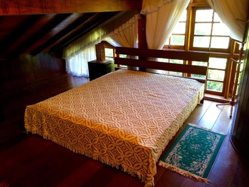a bedroom with a bed in a room with windows at O Silêncio que Canta in Águas de Lindóia
