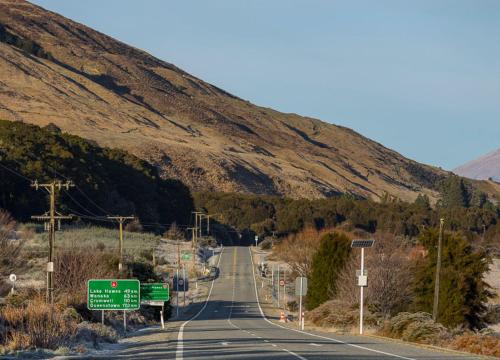 an empty road with a mountain in the background at Wonderland Makarora Lodge in Makarora