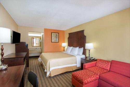 Una habitación de hotel con una cama y un sofá rojo. en Days Inn by Wyndham Blytheville, en Blytheville