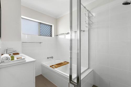 a white bathroom with a shower and a sink at Surfside Apartment 11 by Kingscliff Accommodation in Kingscliff