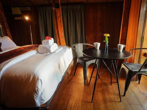 a bedroom with a bed and a table and chairs at MaliHom Private Estate in Balik Pulau