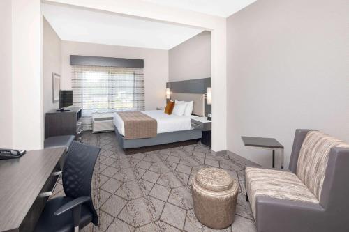 a hotel room with a bed and a couch at Wingate by Wyndham Greenville Airport in Greenville