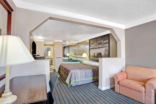 a hotel room with a bed and a chair at Super 8 by Wyndham Knoxville East in Knoxville