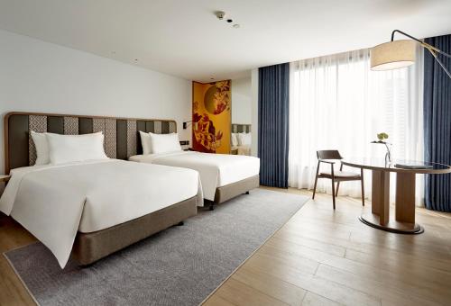 a hotel room with two beds and a table at Montien Hotel Surawong Bangkok in Bangkok