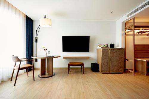 a living room with a tv and a table at Montien Hotel Surawong Bangkok in Bangkok