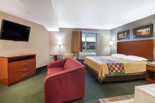 a hotel room with a bed and a chair at Super 8 by Wyndham Clearfield in Clearfield