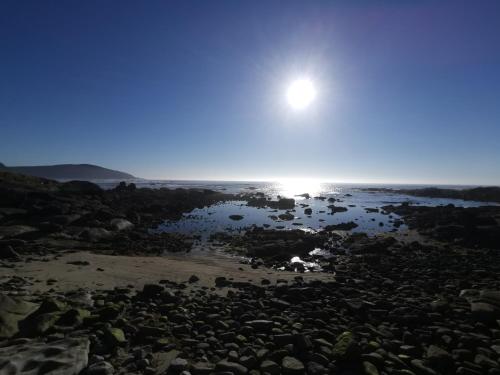 a view of the sun setting over the beach at Alumar Apartamentos Muxia in Muxia