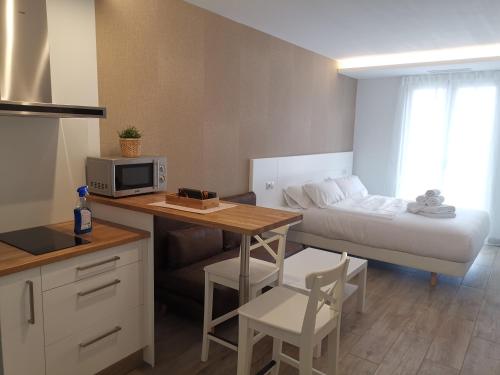 a small room with a bed and a table with a microwave at Alumar Apartamentos Muxia in Muxia