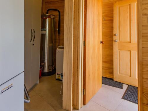 a hallway with a door open to a kitchen with a boiler at The Snowglobe - Ohakune Modern Yurt Style Chalet in Ohakune