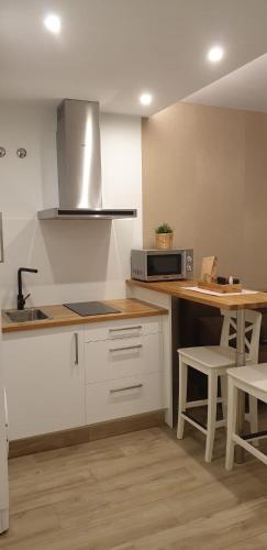 a kitchen with white cabinets and a table and a microwave at Alumar Apartamentos Muxia in Muxia