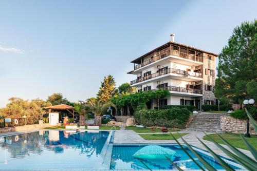 a house with a swimming pool in front of a building at Theoxenia Apartments in Ormos Panagias