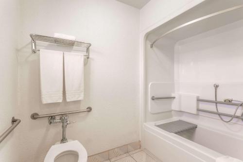 a white toilet sitting next to a bath tub in a bathroom at Days Inn by Wyndham Airport - Phoenix in Phoenix