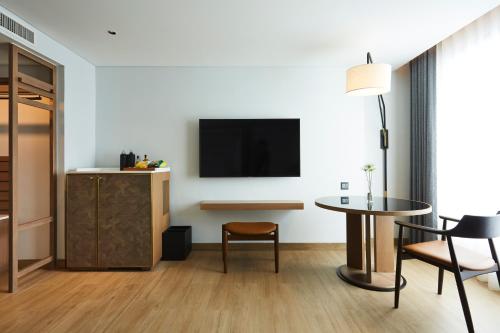 a living room with a table and a tv on a wall at Montien Hotel Surawong Bangkok in Bangkok