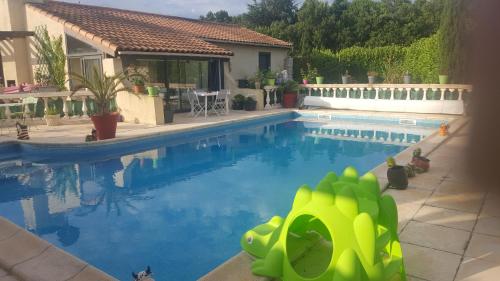 a swimming pool with a green toy in front of a house at Gîte indépendant in Caux-et-Sauzens