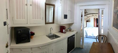 a kitchen with white cabinets and a sink and a bed at Near the pier in Astoria, Oregon
