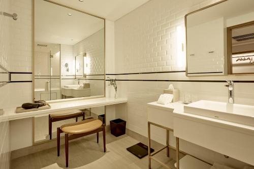 a white bathroom with a sink and a mirror at Montien Hotel Surawong Bangkok in Bangkok
