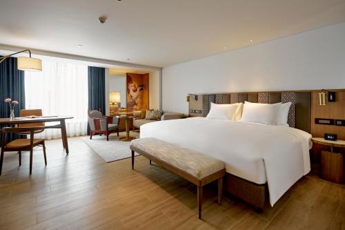 バンコクにあるMontien Hotel Surawong Bangkokの白い大型ベッド1台、デスクが備わる客室です。