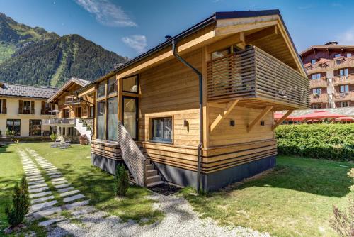 una casa de madera en un patio con montañas al fondo en Chalet des Sapins, en Chamonix-Mont-Blanc