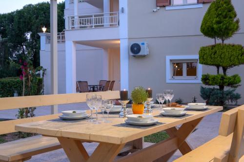 a wooden table with plates and wine glasses on it at KTENA RESIDENCE-Ktena Accomodation in Nydri