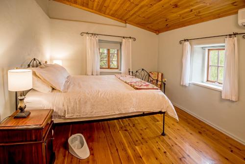 1 dormitorio con 1 cama grande y suelo de madera en Lucy's Cottage en Marananga