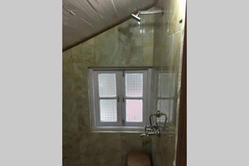 a bathroom with a shower and a window at Pradhan's Cottages in Darjeeling