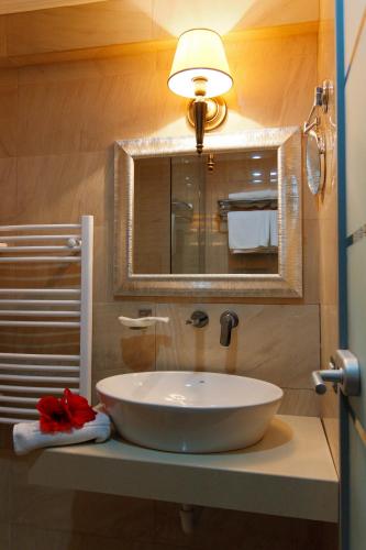 a bathroom with a sink and a light and a mirror at Hotel Roman by Dumbrava Business Resort in Roman