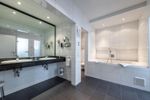 a bathroom with two sinks and a tub at Trip Inn Hotel Esplanade, Düsseldorf in Düsseldorf