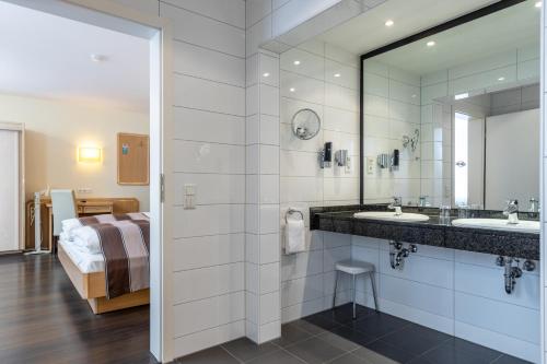 ein Bad mit einem Waschbecken, einem Spiegel und einem Bett in der Unterkunft Trip Inn Hotel Esplanade in Düsseldorf