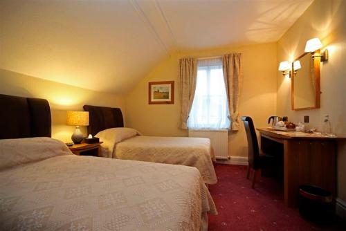 a hotel room with two beds and a desk and a window at Eskdale Lodge in Sale