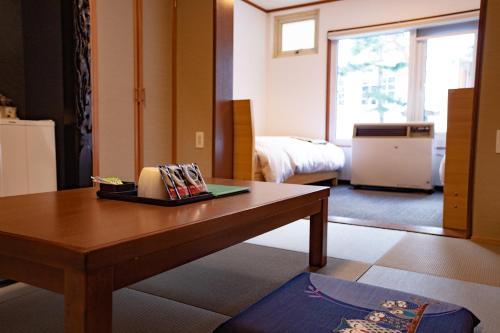 um quarto com uma mesa e um quarto com uma cama em CHALET BURLAP FURANUI em Furano
