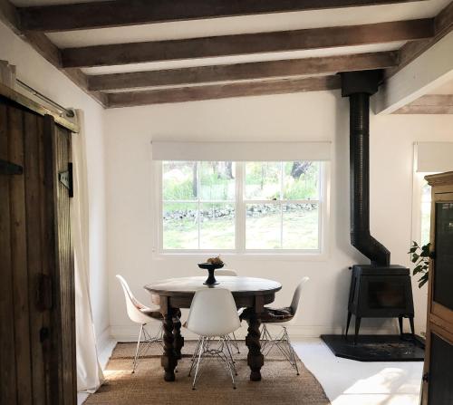 ein Esszimmer mit Tisch und Stühlen und einem Fenster in der Unterkunft Cottage At 31 in Bundanoon