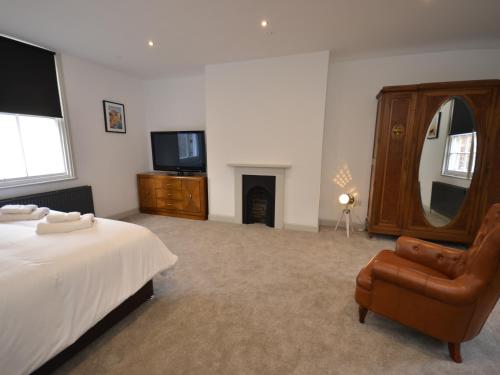 a bedroom with a bed and a chair and a television at The Chapel House in Scarborough